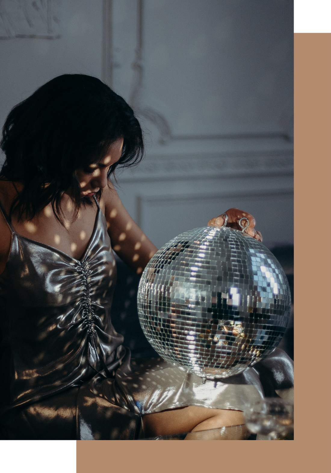  black woman with black hair wearing a silver dress staring at a disco ball